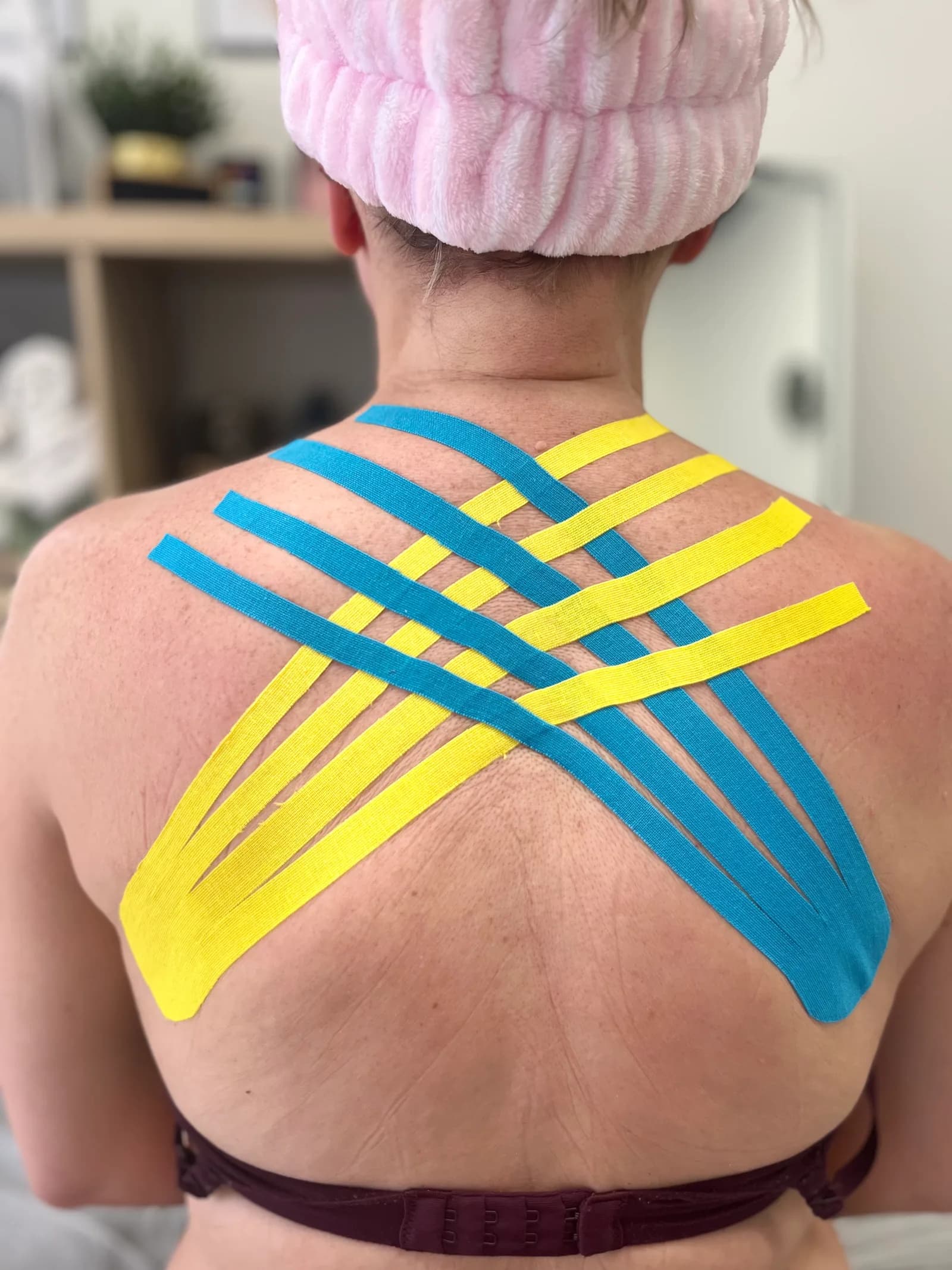 Blue and yellow kinesio taping across a client’s upper back